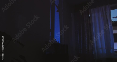 Cinematic 4k DCI scene of home apartment house interior view with emergency lights from rescue ambulance police beacon light working reflected on walls from the street - dusk outdoor scene