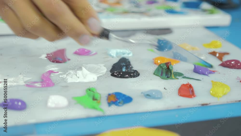 Artist taking bright colourful acrylic paint with spatula Artist taking bright colourful acrylic paint with spatula