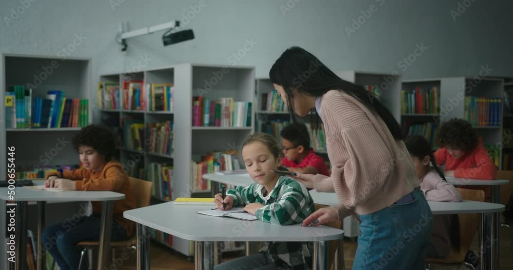 Asian teacher uses tablet checking learning process of kids Asian teacher uses tablet checking learning process of kids