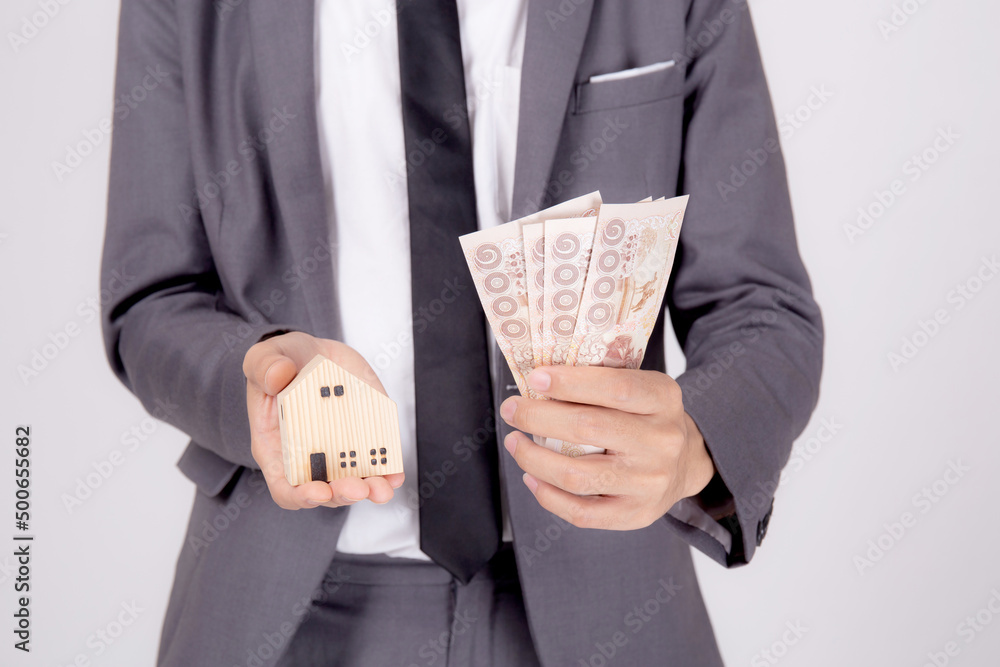 Young asian business man holding home and money Thai for planning saving future, insurance agent and credit, debt and loan of finance, purchase home and refinance, investment about real property. Young asian business man holding home and money Thai for planning saving future, insurance agent and credit, debt and loan of finance, purchase home and refinance, investment about real property.