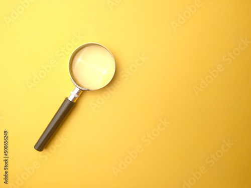Magnifying glass on a yellow background with copy and text space.
