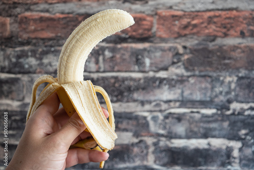 人の手で持ったバナナ。皮を剥いて食べるところ。