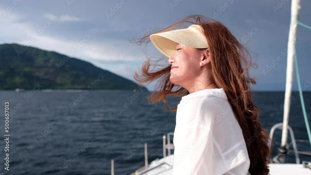 Slow motion of a young woman sitting and relaxing on yacht deck boat while sailing in the sea Slow motion of a young woman sitting and relaxing on yacht deck boat while sailing in the sea