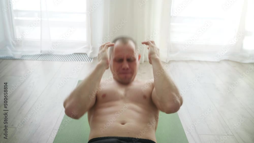 Home workout in the living room. Young muscular body topless man doing abs stomach muscles exercises. Healthy lifestyle, motivation and sporty people 4K footage. Home workout in the living room. Young muscular body topless man doing abs stomach muscles exercises. Healthy lifestyle, motivation and sporty people 4K footage.