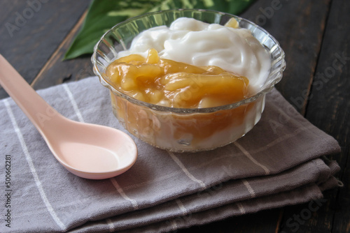 Sweet Rice Noodles with Coconut Cream served in a glass cup on a black wooden table.