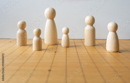 Wooden Figure of Various Size Placing on Chess Board Representing DIversity of People and Family