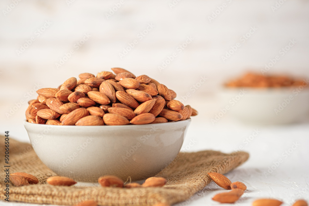 Almonds in ceramic bowl on white wood table.organic Diet raw material Almonds in ceramic bowl on white wood table.organic Diet raw material