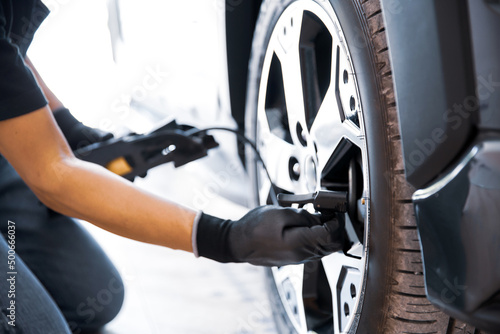 Auto mechanic checking air pressure and inflating car tires. Concept of car care service and maintenance or fix the car leaky or flat tire.