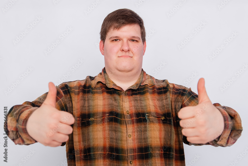 Fototapeta premium Fat guy showing thumbs up with both hands isolated on white background. Young man making a gesture, I like it, great job. Body language, body positivity. 