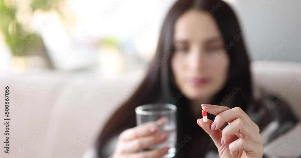 Young woman is holding pill and glass of water Young woman is holding pill and glass of water
