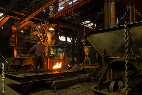 Metallurgist pouring hot molten metal out of furnace