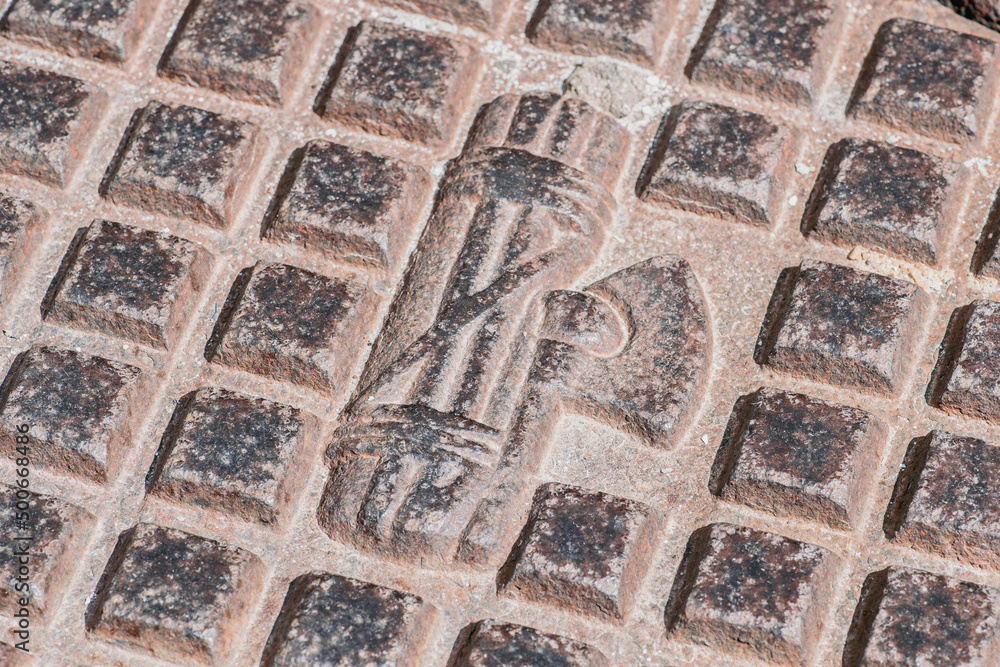 Faded symbol of Fascism on a manhole of the sewer or water system, Mottola, Puglia, Italy Faded symbol of Fascism on a manhole of the sewer or water system, Mottola, Puglia, Italy