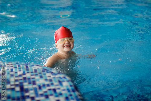 A child in a cap and glasses swims dives in the pool
