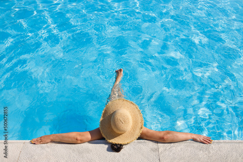 top view of woman in straw hat relaxing in swimming pool