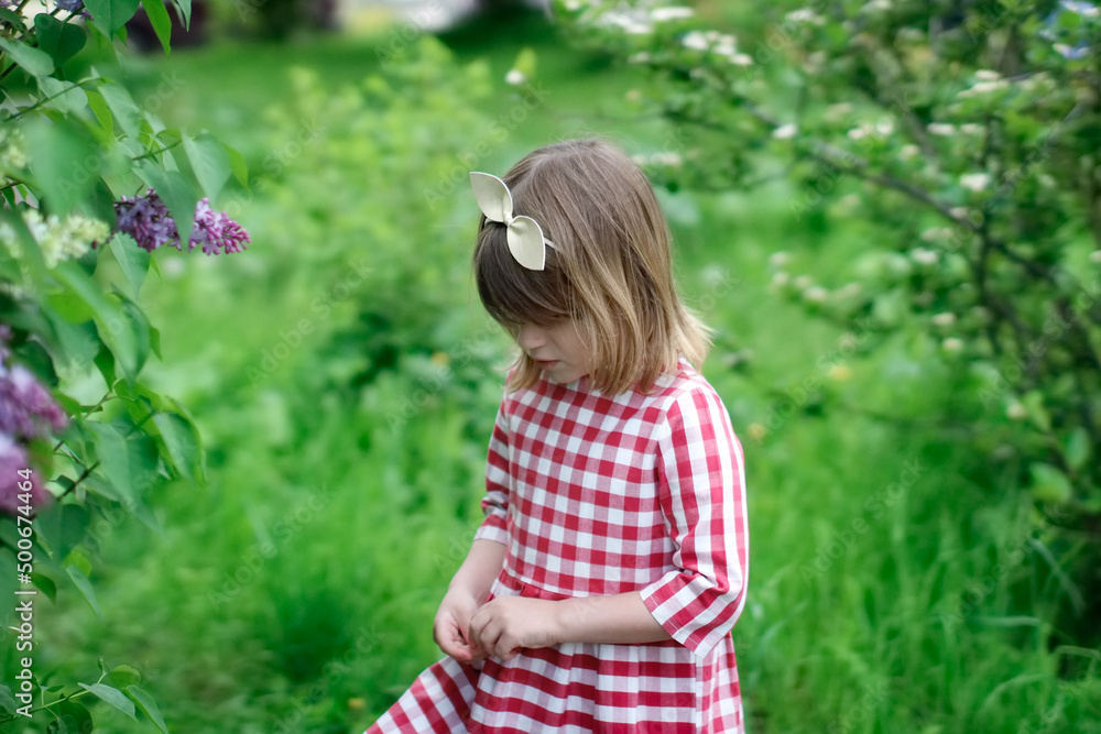 Cute child girl with headband with bow among spring green