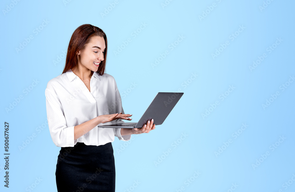 Fototapeta premium Young office woman typing on laptop, mockup blue background