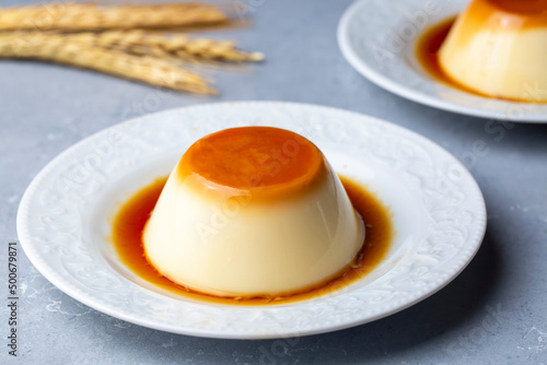 Cream caramel pudding with caramel sauce in plate on white rustic table photo