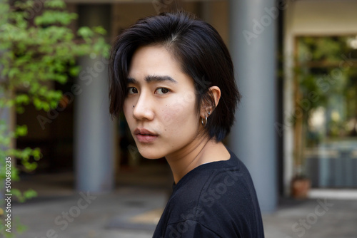 Upset asian non-binary LGBT person looking back with unhappy mood