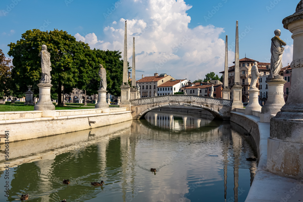 Scenic view on bridge of Prato della Valle, square in the city of Padua, Veneto, Italy, Europe. Green island at center, Isola Memmia surrounded by canal. Ducks are swimming in the water