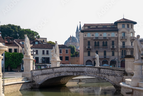 Scenic view on bridge of Prato della Valle, square in the city of Padua, Veneto, Italy, Europe. Green island at center, Isola Memmia surrounded by canal bordered by two rings of statues. Reflection
