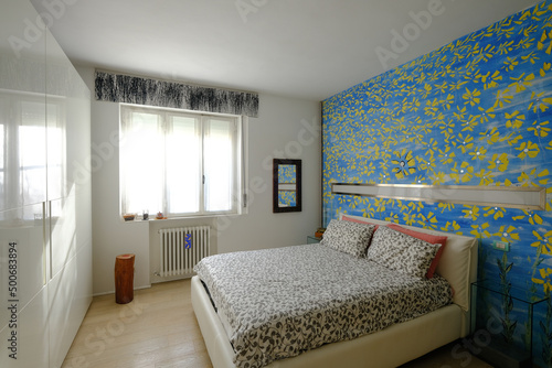 Interior of modern comfortable bedroom with sunflowers on blue color wall
