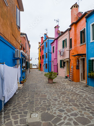 Colorful houses of Burano island. Multicolored buildings on fondamenta embankment of narrow water canal with fishing boats and stone bridge, Venice Province, Veneto Region, Italy. Burano postcard © scimmery1