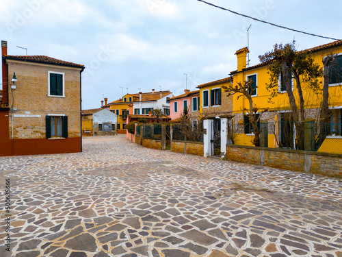 Colorful houses of Burano island. Multicolored buildings on fondamenta embankment of narrow water canal with fishing boats and stone bridge, Venice Province, Veneto Region, Italy. Burano postcard photo