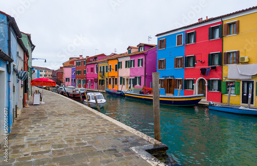 Colorful houses of Burano island. Multicolored buildings on fondamenta embankment of narrow water canal with fishing boats and stone bridge, Venice Province, Veneto Region, Italy. Burano postcard