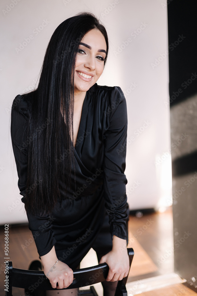 Beautiful brunette woman in elegant black dress. Female with evening makeup. Studio photo shoot
