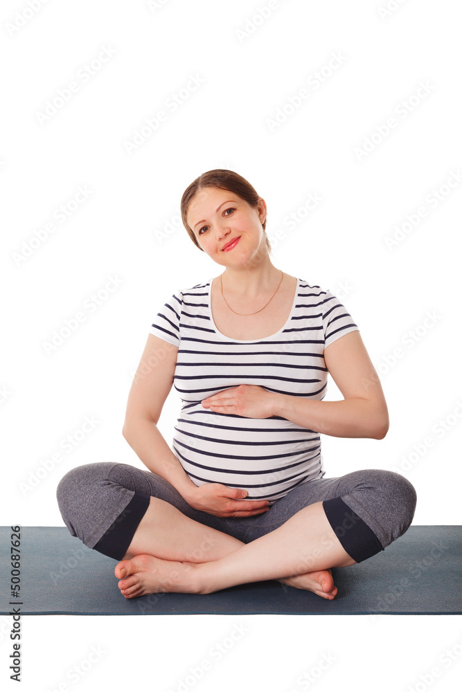 Pregnancy yoga exercise - pregnant woman doing asana Sukhasana easy yoga pose embracing her belly isolated on white background