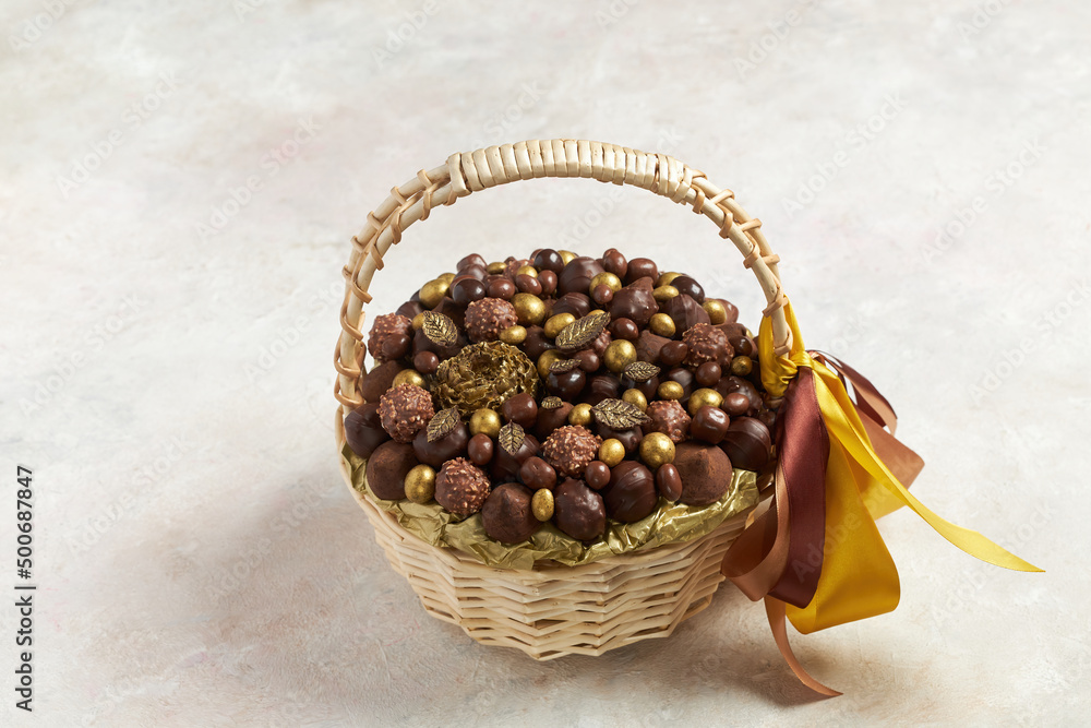 A lot of different delicious chocolate candies lie in a basket on a gray background A lot of different delicious chocolate candies lie in a basket on a gray background