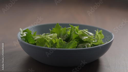 making salad, frisee lettuce in blue bowl on wood table
