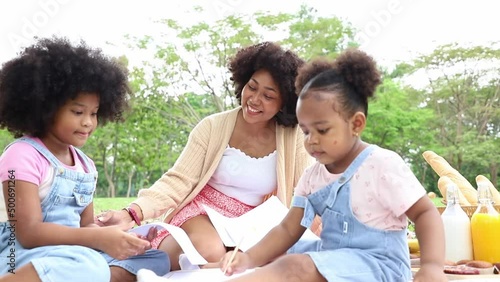 Beautiful mother teach and introduced quality of red apple to daughter while relax and picnic in public park. Summertime in the last weekend.