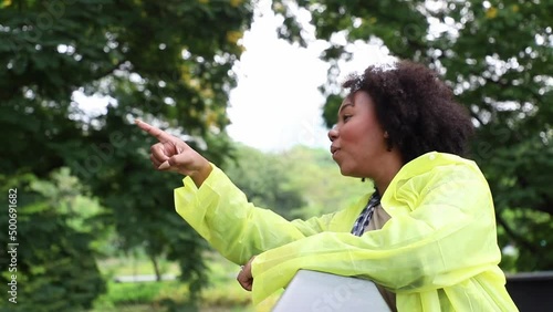 Rainy day, Positive young woman wearing yellow raincoat during the rain in the park. Dodge and run away from the rain in a joyful manner and natural.
