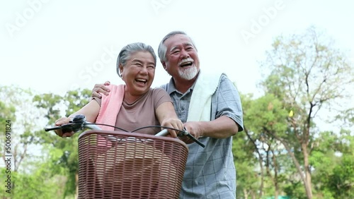 An elderly couple enjoys cycling and relaxing in the park with bright smiles and enjoys relaxing after retirement. Healthy and insurance concept