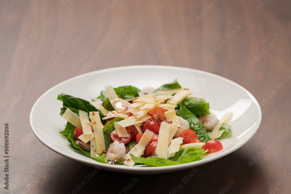 Salad with shrimps, tomatoes and romaine lettuce on white plate Salad with shrimps, tomatoes and romaine lettuce on white plate