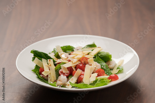 Salad with shrimps, tomatoes and romaine lettuce on white plate