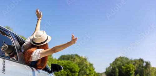 Woman put her hands up in the air and out of the car with enjoyment and happiness for solo road trip summer vacation and weekend travel freedom concept with copy space photo