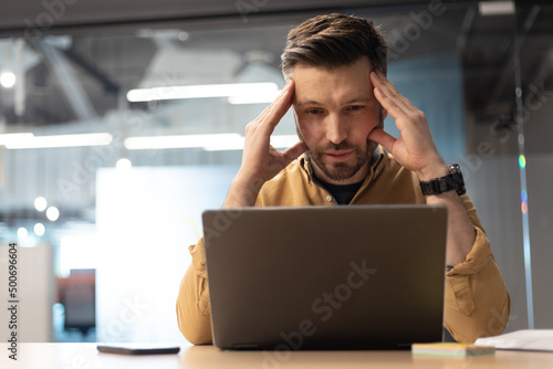 Concerned Businessman Using Laptop Having Problem Sitting In Modern Office