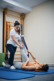 Physical therapist assists her patient with exercising at health club.