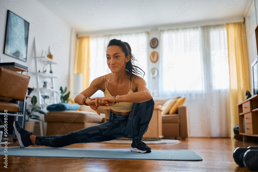 Female athlete doing stretching exercise while practicing at home. Female athlete doing stretching exercise while practicing at home.