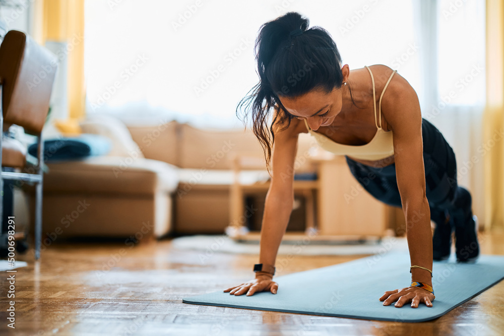 Athlete practicing push-up while working out in her living rom. Athlete practicing push-up while working out in her living rom.