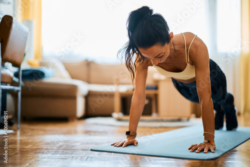 Athlete practicing push-up while working out in her living rom. photo