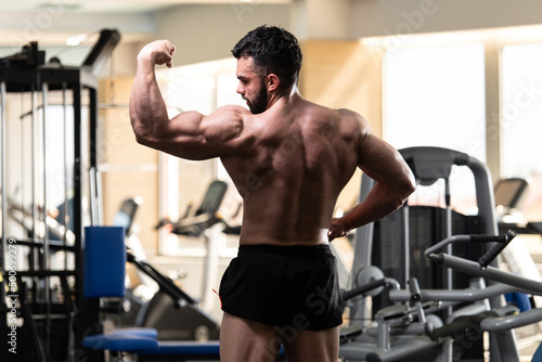 Biceps Pose Of A Young Man In Gym