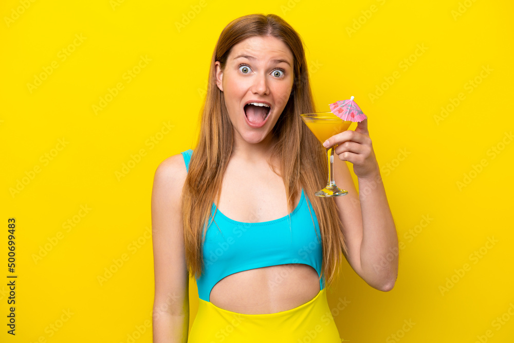 Young caucasian woman holding a cocktail isolated on yellow background with surprise and shocked facial expression Young caucasian woman holding a cocktail isolated on yellow background with surprise and shocked facial expression