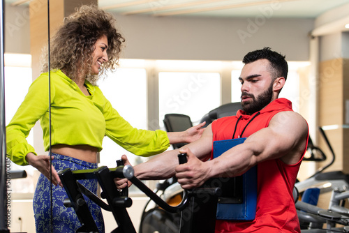Gym Coach Helping Man On Exercising Back