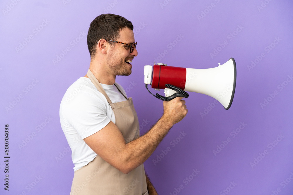 Brazilian restaurant waiter over isolated purple background shouting through a megaphone Brazilian restaurant waiter over isolated purple background shouting through a megaphone