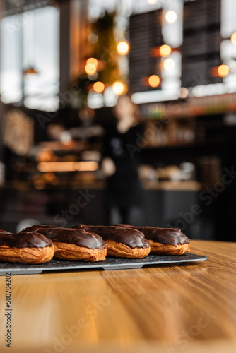 Tasty chocolate eclairs on slate plate in cafe. Delicious pastries for coffee. Isolated eclairs on the wood table