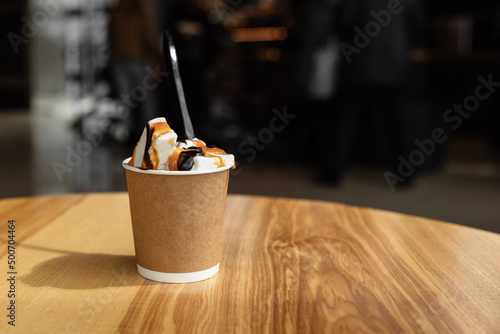 Ice cream with coffee in a disposable cup to take away. Isolated paper cup with ice cream on the table in a cafe