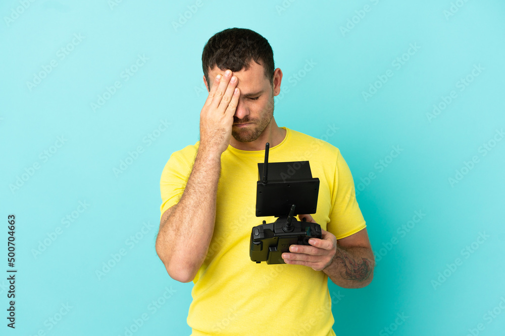 Brazilian man holding a drone remote control over isolated blue background with tired and sick expression Brazilian man holding a drone remote control over isolated blue background with tired and sick expression